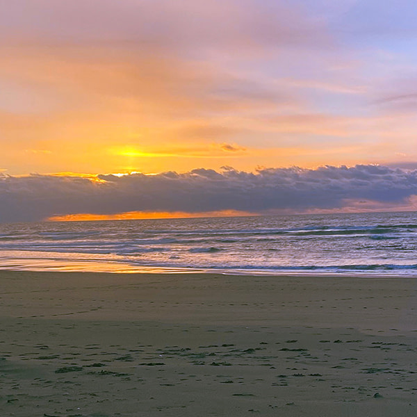 Hers, pastel blues and yellow orange, brushing a silver Pacific.